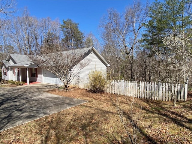 view of side of property with fence, a garage, and driveway