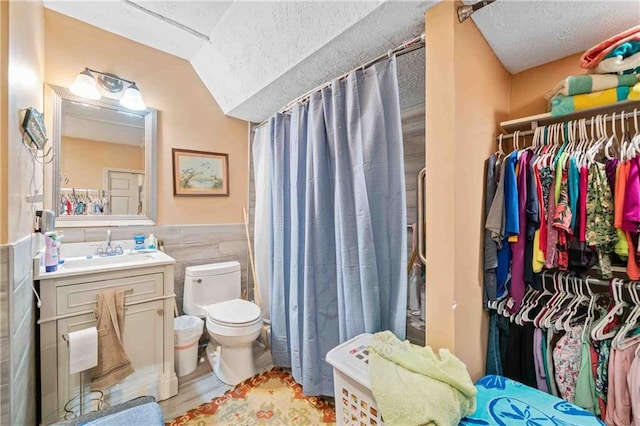592 Ferry Creek Ct, Acworth, GA 30102 - full bath with tile walls, a textured ceiling, vanity, a spacious closet, and a wainscoted wall