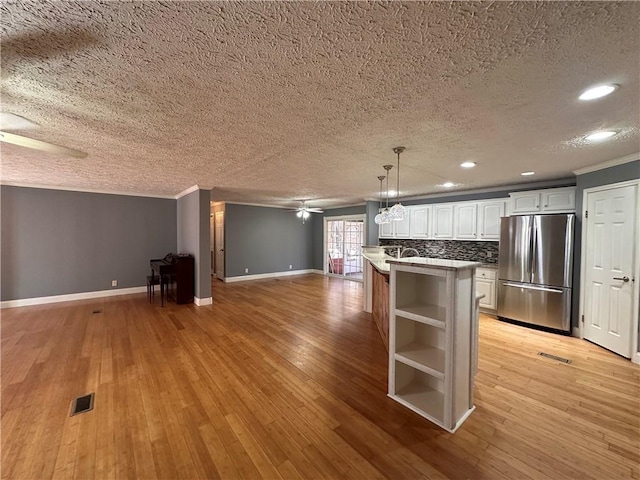 kitchen with light hardwood / wood-style flooring, a center island, white cabinetry, hanging light fixtures, and stainless steel refrigerator