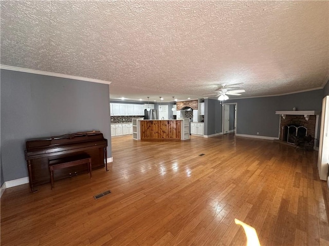 unfurnished living room with hardwood / wood-style floors, a fireplace, ceiling fan, and a textured ceiling