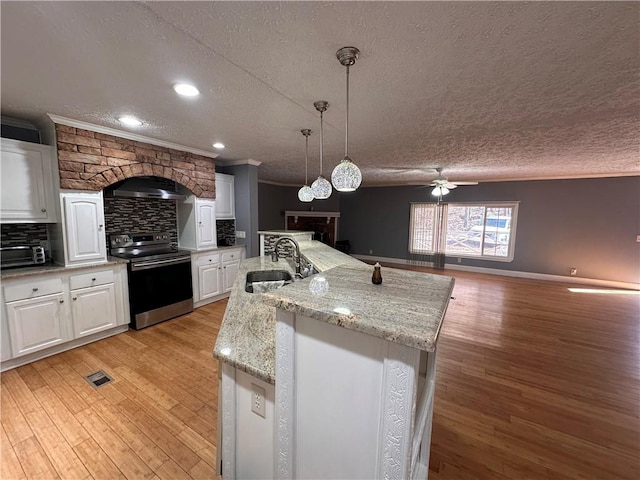 kitchen featuring sink, light hardwood / wood-style flooring, a large island, stainless steel range oven, and white cabinetry