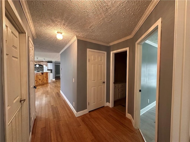 hall with hardwood / wood-style floors, crown molding, and a textured ceiling