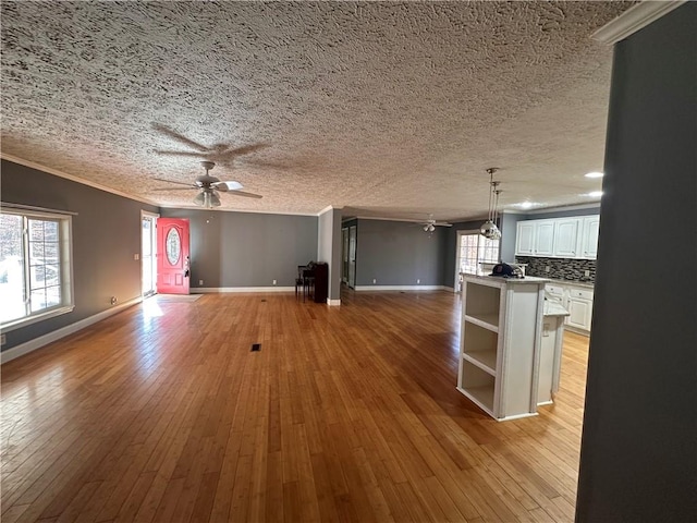 unfurnished living room featuring ornamental molding, a wealth of natural light, and light hardwood / wood-style flooring