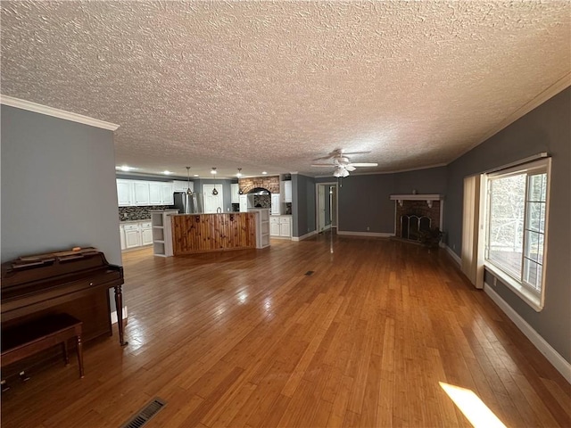 unfurnished living room featuring hardwood / wood-style floors, a large fireplace, a textured ceiling, and crown molding