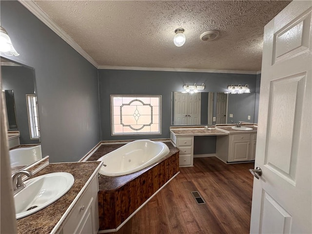 bathroom featuring wood-type flooring, vanity, a textured ceiling, and ornamental molding