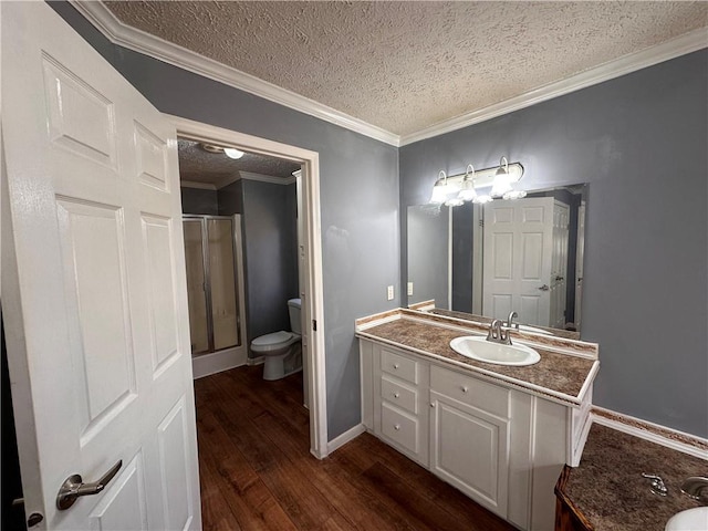 bathroom featuring hardwood / wood-style floors, vanity, toilet, ornamental molding, and a textured ceiling