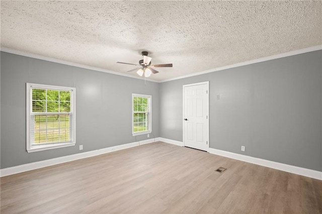 empty room with hardwood / wood-style floors, ornamental molding, a textured ceiling, and a wealth of natural light