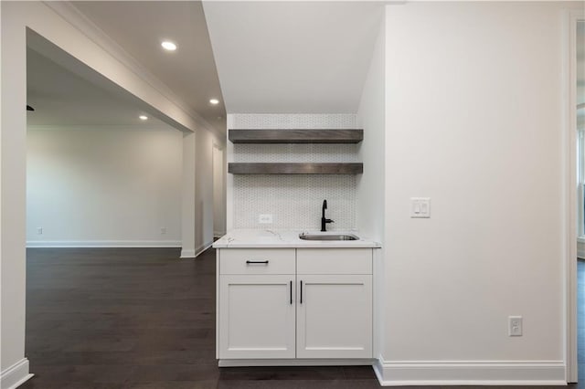 bar featuring tasteful backsplash, ornamental molding, dark wood-type flooring, sink, and white cabinetry