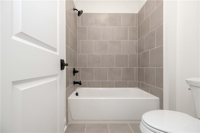 bathroom featuring toilet, tiled shower / bath combo, and tile patterned floors