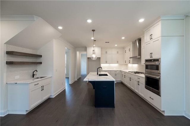 kitchen with a center island with sink, wall chimney exhaust hood, white cabinets, and sink