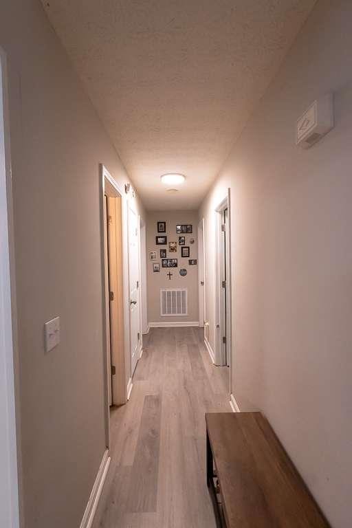 hallway featuring light hardwood / wood-style floors and a textured ceiling