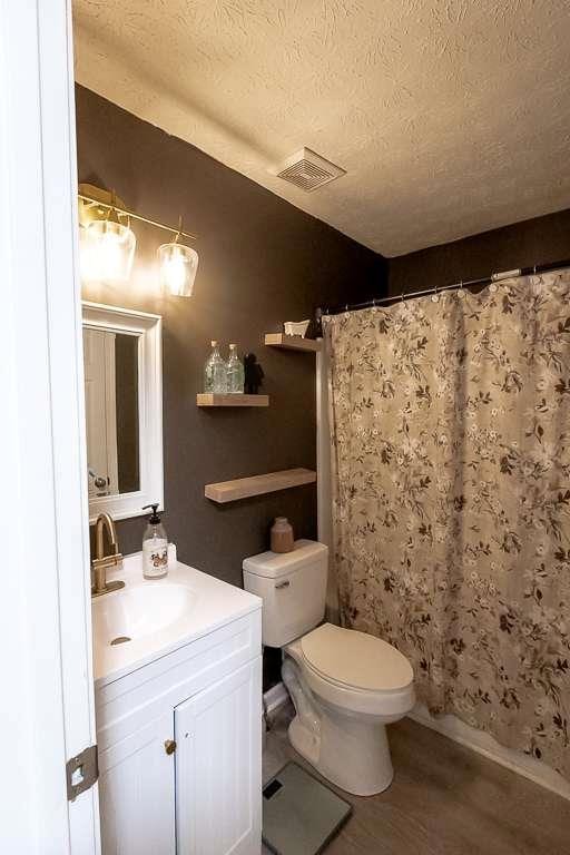 bathroom featuring hardwood / wood-style flooring, vanity, toilet, a textured ceiling, and a shower with shower curtain