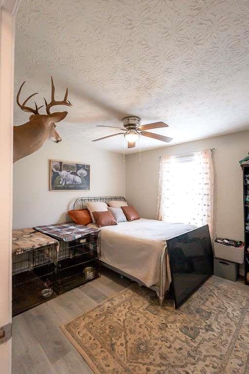 bedroom with ceiling fan, hardwood / wood-style floors, and a textured ceiling