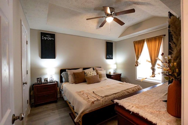 bedroom with vaulted ceiling, dark hardwood / wood-style flooring, ceiling fan, and a textured ceiling