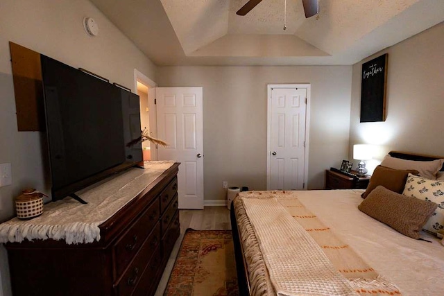 bedroom featuring ceiling fan, a tray ceiling, and light hardwood / wood-style floors