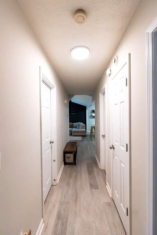 hallway featuring light hardwood / wood-style flooring and a textured ceiling