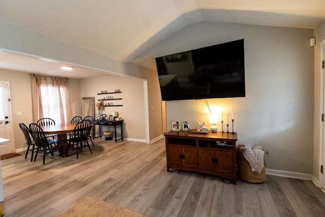 dining space featuring hardwood / wood-style floors and vaulted ceiling