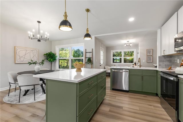 kitchen with white cabinets, appliances with stainless steel finishes, an inviting chandelier, a sink, and green cabinets