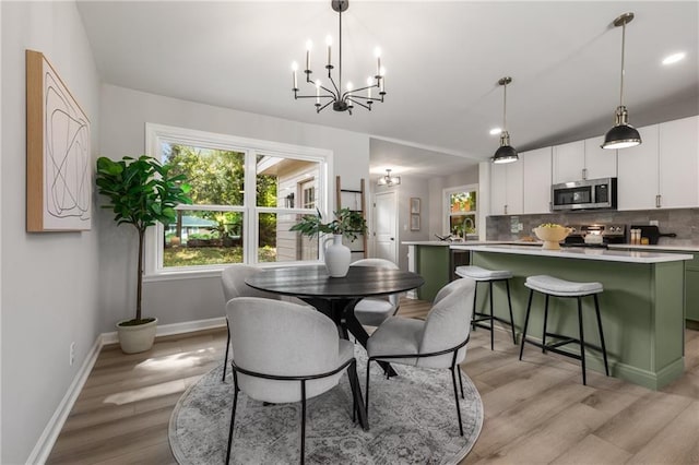 dining space with baseboards, an inviting chandelier, and light wood-style flooring