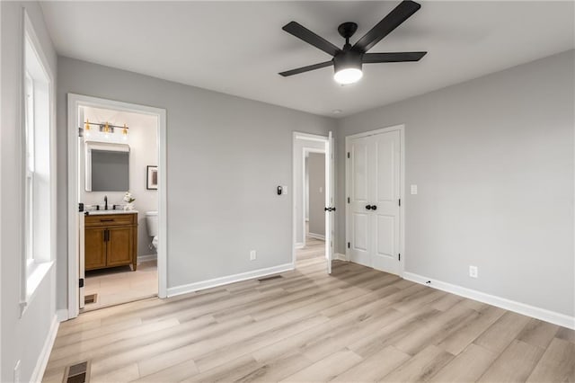 unfurnished bedroom featuring visible vents, baseboards, a closet, light wood-style floors, and ensuite bath