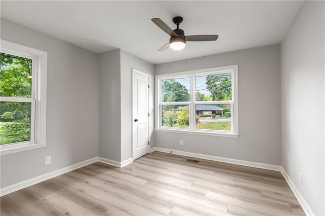 spare room with light wood-style floors, baseboards, plenty of natural light, and visible vents