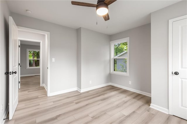 spare room with baseboards, a ceiling fan, and light wood finished floors