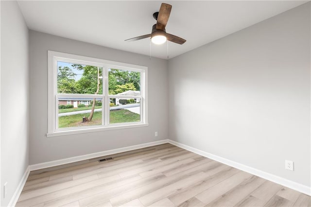 spare room featuring baseboards, ceiling fan, light wood-style flooring, and visible vents