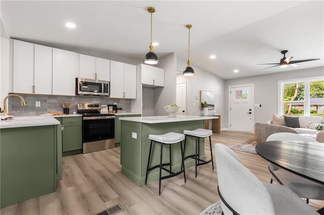 kitchen featuring stainless steel appliances, white cabinetry, light wood-type flooring, backsplash, and green cabinets