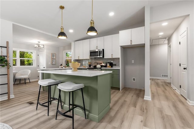 kitchen featuring light wood-style floors, a center island, stainless steel microwave, and range