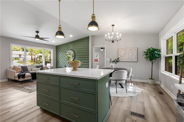 kitchen featuring light wood finished floors, a center island, green cabinetry, and visible vents