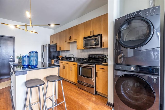 5300 Peachtree Rd Unit 3206, Atlanta, GA 30341 - kitchen featuring light wood-style floors, stacked washing maching and dryer, dark countertops, and appliances with stainless steel finishes