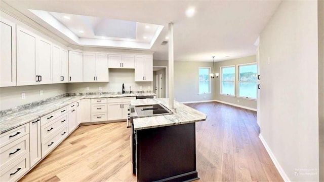137 Rockville Springs Ct, Eatonton, GA 31024 - kitchen featuring a sink, light wood finished floors, a raised ceiling, white cabinetry, and a kitchen island