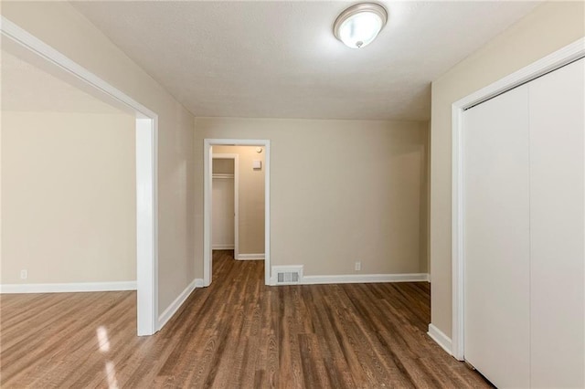 unfurnished bedroom with dark wood-type flooring and a closet