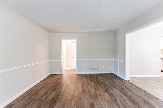 empty room featuring dark wood-type flooring and a textured ceiling