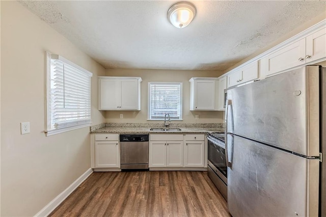 kitchen featuring sink, white cabinetry, appliances with stainless steel finishes, dark hardwood / wood-style flooring, and light stone countertops