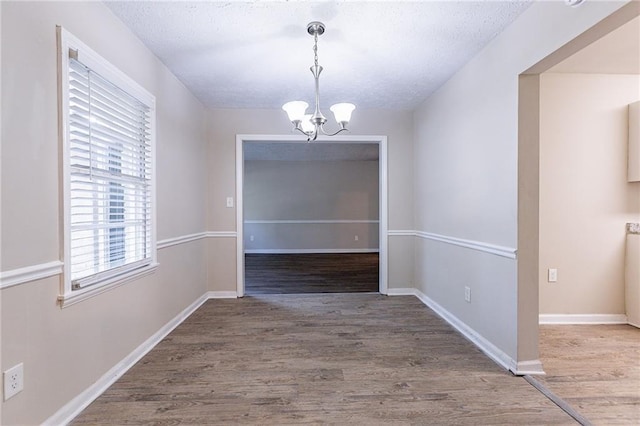 unfurnished dining area with a notable chandelier and hardwood / wood-style flooring