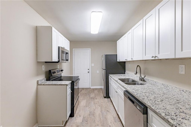 kitchen featuring light stone countertops, white cabinetry, appliances with stainless steel finishes, and sink