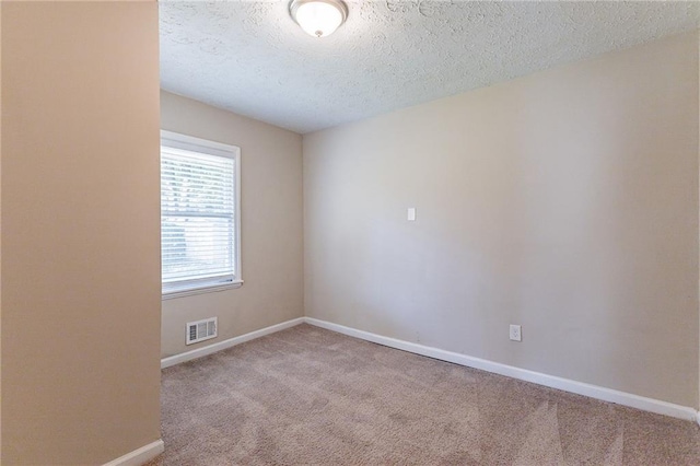 spare room with light carpet and a textured ceiling