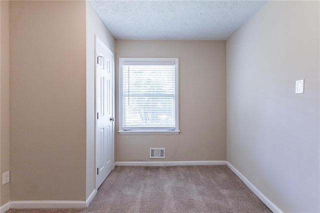 carpeted empty room with a textured ceiling