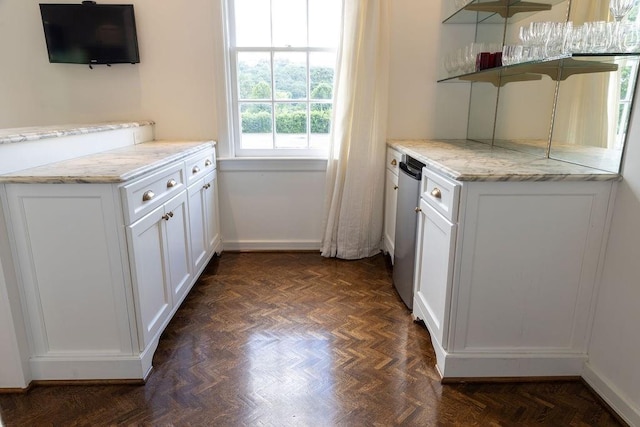 kitchen featuring white cabinets, light stone counters, open shelves, and stainless steel dishwasher