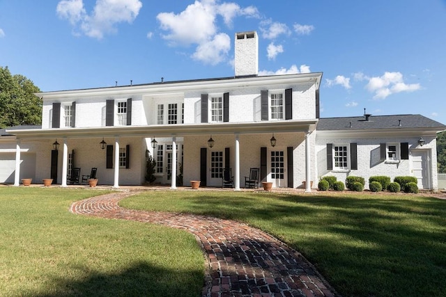 rear view of house with brick siding, a lawn, and a chimney