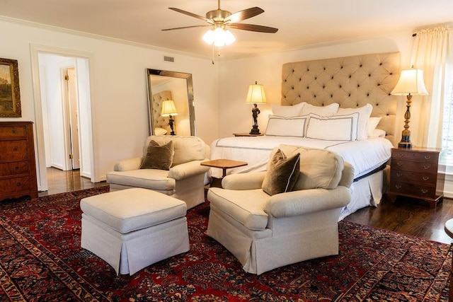 bedroom with dark wood-type flooring, a ceiling fan, visible vents, and crown molding