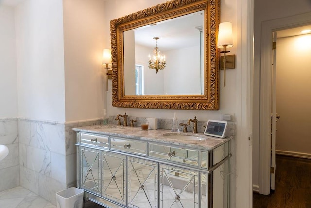 full bathroom with double vanity, tile walls, a sink, and wainscoting