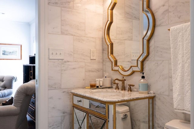 ensuite bathroom featuring tile walls, vanity, toilet, and ensuite bathroom