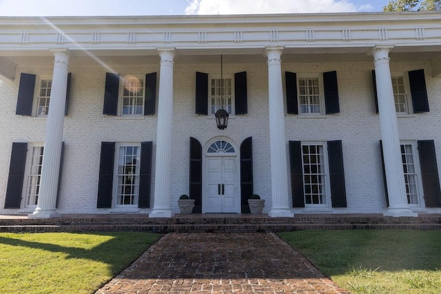 exterior space featuring a porch, a lawn, and brick siding