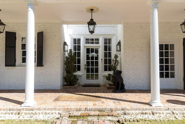 doorway to property with covered porch, french doors, and brick siding