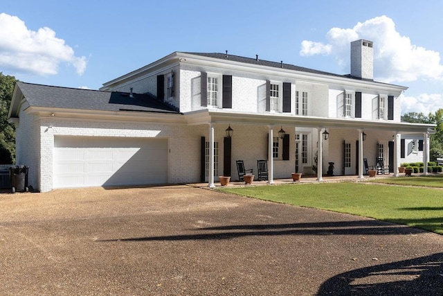 view of front facade with a garage, a chimney, aphalt driveway, and brick siding