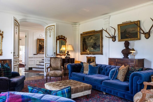 living area featuring ornate columns, stairway, and crown molding