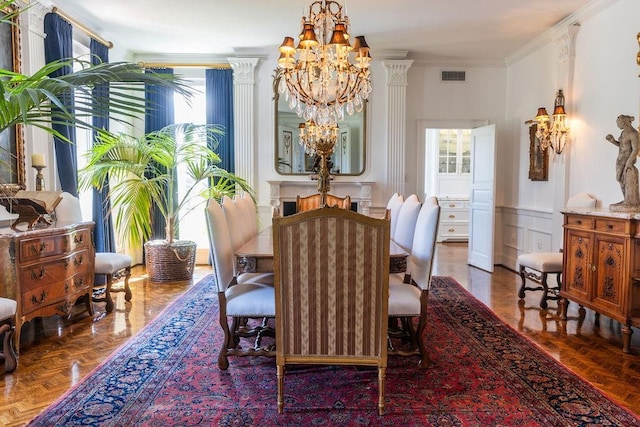 dining area featuring a decorative wall, a wainscoted wall, a notable chandelier, visible vents, and ornamental molding