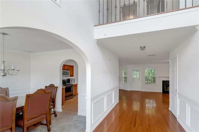 11354 Conner Ct, Hampton, GA 30228 - hall featuring a decorative wall, wainscoting, ornamental molding, light wood-style floors, and a chandelier